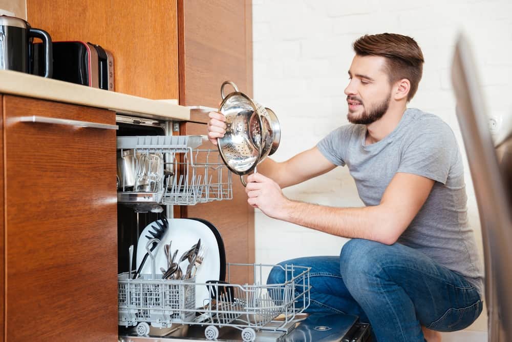 Man inspecting clean dishes from dishwasher on water softener system