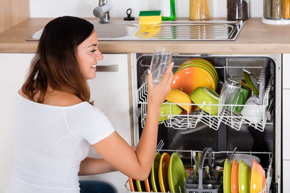 Woman inspects clean and clear glass from dishwasher on a water softener system